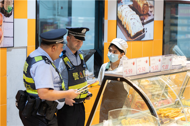 民警在沿街烘焙店检查从业人员健康证明和食材储存条件，督促经营者把好食品安全每一道关口。