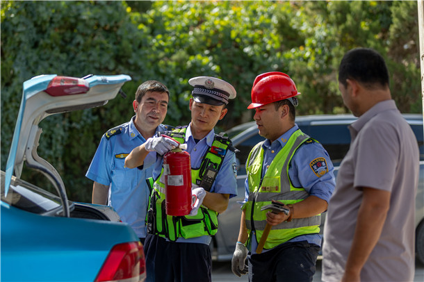 交警在路面检查中逐车查看车载灭火器配备及有效期，确保安全设施齐全有效。